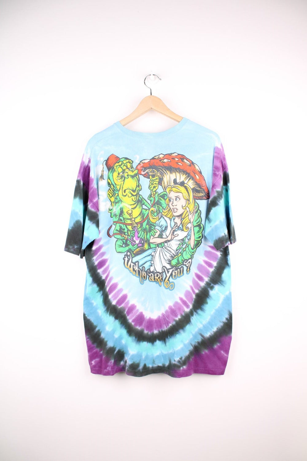 Alice in Wonderland T-Shirt in a multicoloured tie dye colourway with cartoon graphic printed on the front with 'Don't you know you're all mad here' spell out around it. 