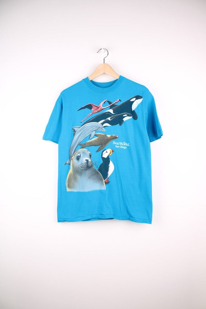 Vintage 80's Sea World San Diego T-Shirt in a blue colourway with Harlequin NG animals graphic printed on the front and back. 