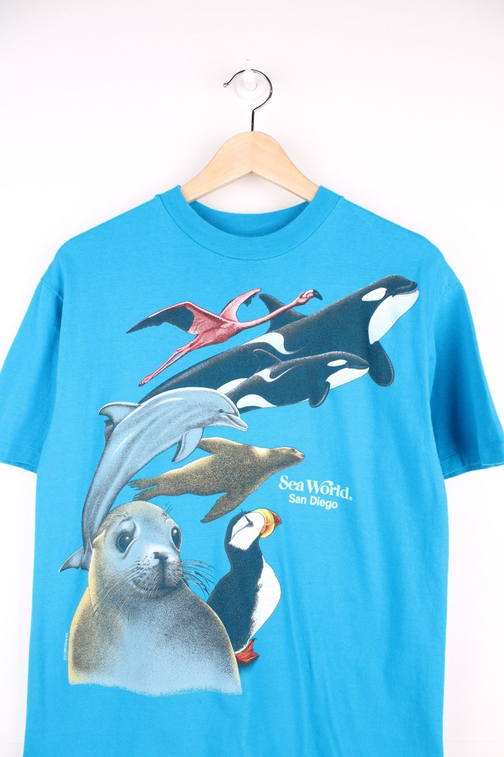 Vintage 80's Sea World San Diego T-Shirt in a blue colourway with Harlequin NG animals graphic printed on the front and back. 