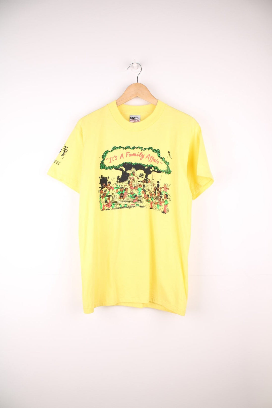 Vintage yellow graphic United Health Plan tee with cartoon design reading 'It's a Family Affair', and a Watts Health Foundation sponsorship logo on the right sleeve. 