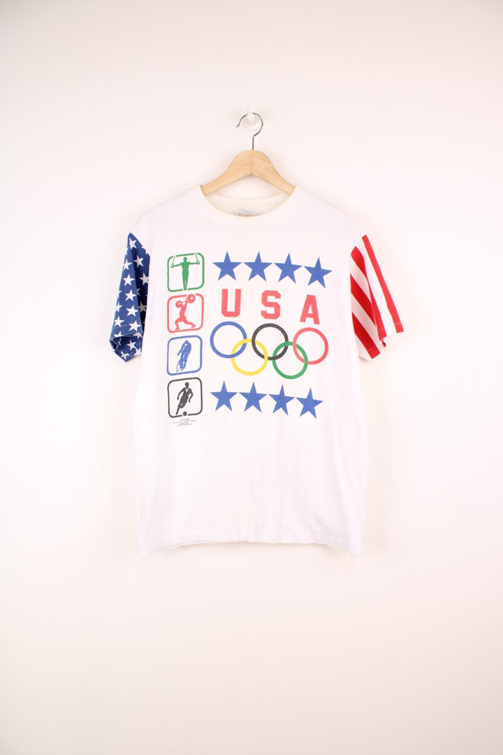 1988 Hanes Olympics USA graphic tee with US flag sleeve designs, and a front graphic of sports illustrations, stars, the Olympic rings, and a USA spellout. 