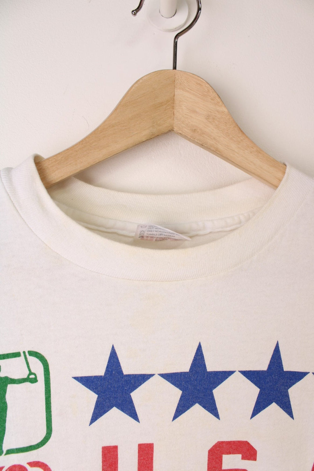 1990 Hanes Olympics USA graphic tee with US flag sleeve designs, and a front graphic of sports illustrations, stars, the Olympic rings, and a USA spellout.