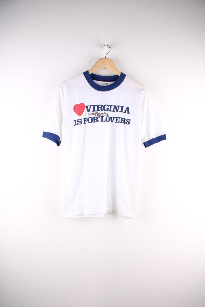  Vintage 1980s Hershey's Chocolate Ringer T Shirt in a white and navy blue colourway. The shirt has a graphic printed on the front, has double stitching on the shoulder seams and has a single stitch hem. 