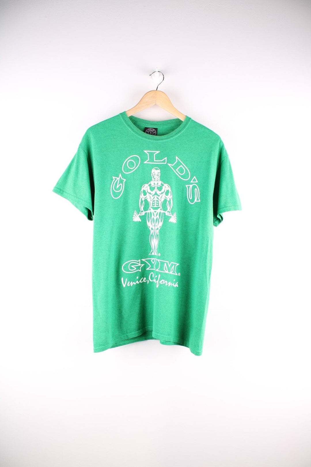 Vintage Gold's Gym T Shirt in a green colourway. The shirt has a large graphic printed on the front. Gold's Gym has a long history of body builders who have trained there, including Arnold Schwarzenegger and Dave Draper. The gym is located on Muscle Beach in Venice Beach, California. 