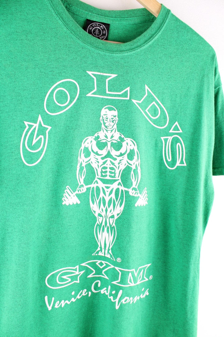 Vintage Gold's Gym T Shirt in a green colourway. The shirt has a large graphic printed on the front. Gold's Gym has a long history of body builders who have trained there, including Arnold Schwarzenegger and Dave Draper. The gym is located on Muscle Beach in Venice Beach, California. 