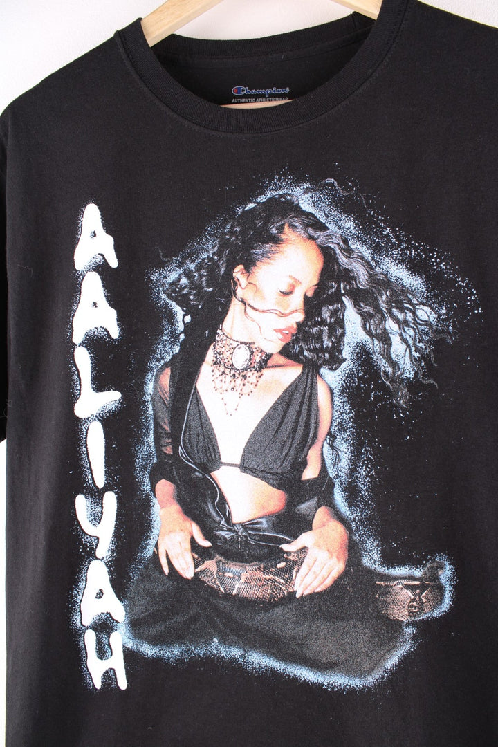 Champion Aaliyah Bumpboxx T-Shirt in black. The shirt has a large printed graphic of Aahliyah on the front and is merchandise from a collab between Champion and Boomboxx. 