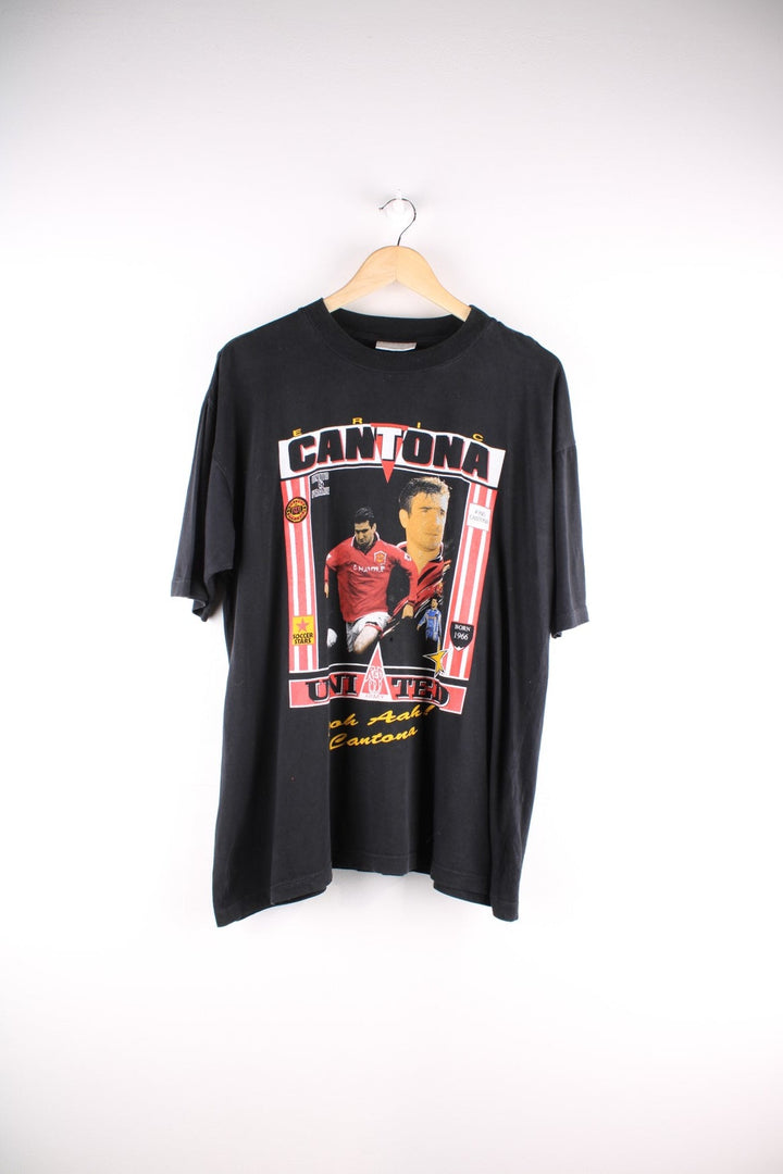 Vintage Eric Cantona T-Shirt in black. The shirt has a large printed graphic on the front, and the famous football chant 'ooh aah Cantona' on the back. Eric Cantona played for Manchester United from 1992 - 96 and has become one the team's most legendary players. 