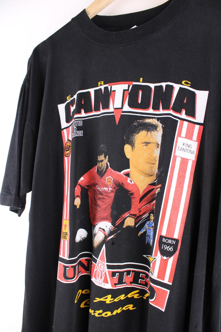 Vintage Eric Cantona T-Shirt in black. The shirt has a large printed graphic on the front, and the famous football chant 'ooh aah Cantona' on the back. Eric Cantona played for Manchester United from 1992 - 96 and has become one the team's most legendary players. 