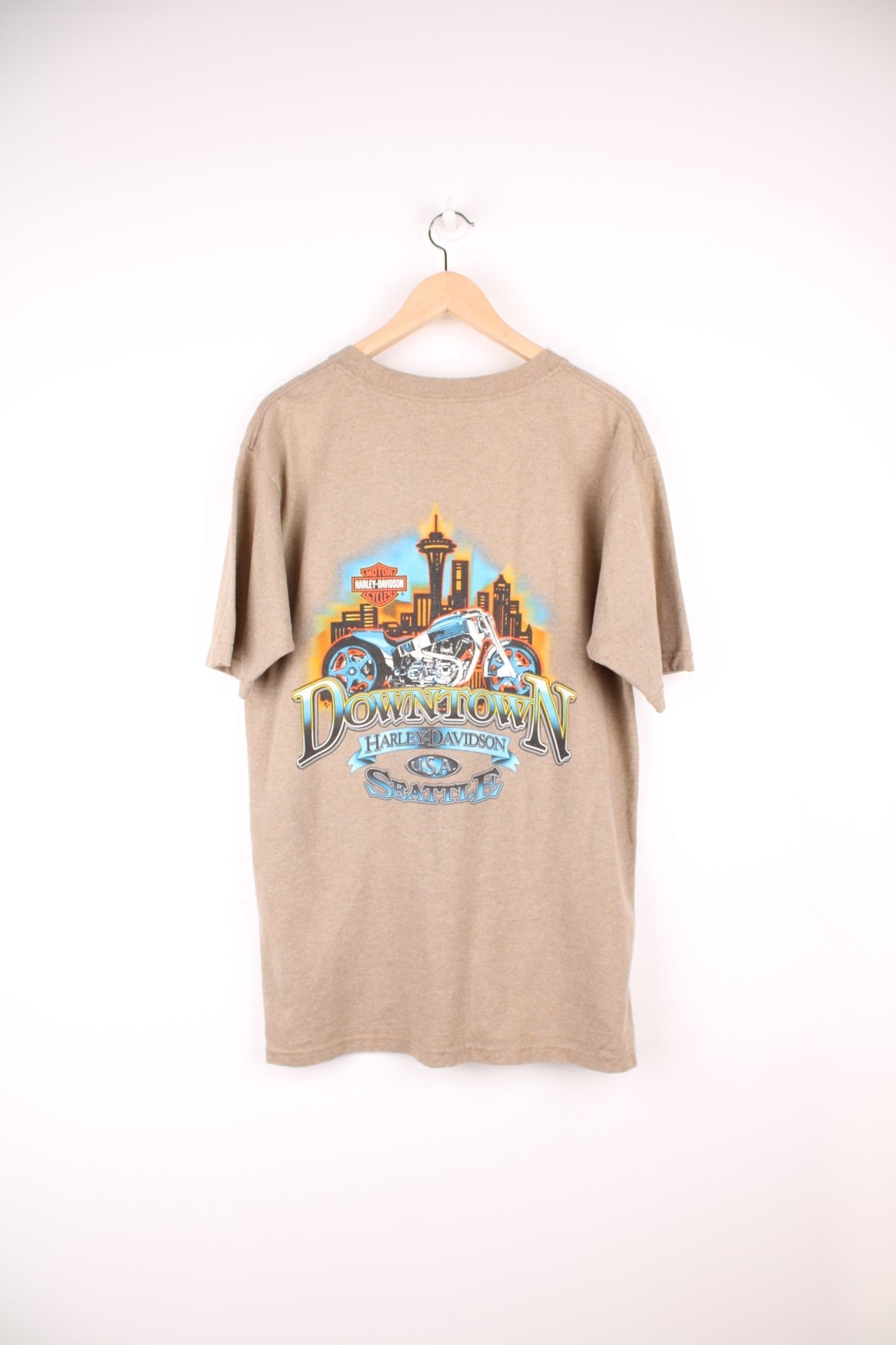 Vintage Harley Davidson Downtown Seattle T-Shirt in light brown. Features printed spell out logo across the chest and graphic print on the back.