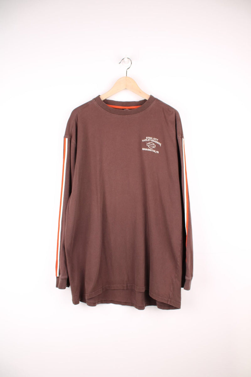 Harley Davidson Steel City, Washington, PA long sleeved top in brown. Features orange and white stripe down each sleeve, and embroidered spell out logo and eagle on the back. 