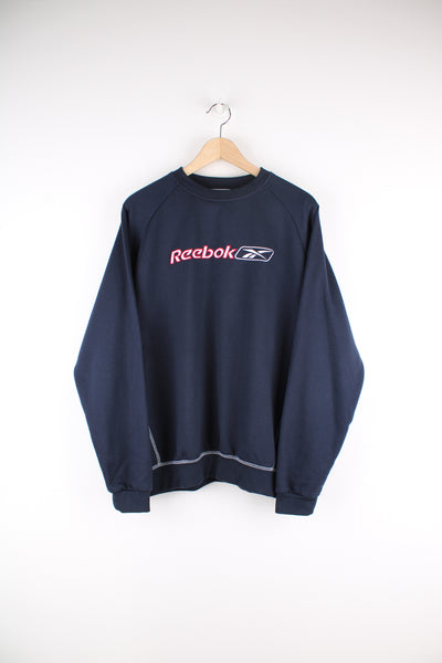 Reebok Sweatshirt in a blue colourway with contrast stitching throughout, crewneck and has the logo spell out embroidered across the front.