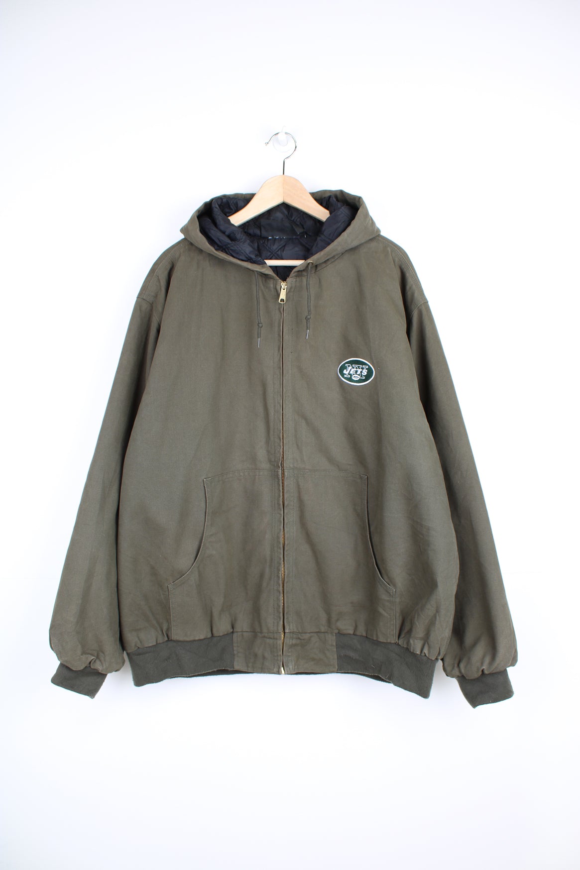 Vintage New York Jets NFL Jacket in a khaki green colourway, workwear style jacket similar to Carhartt Active Jackets, quilted lining, hooded, zip up with side pockets and has the team logo and spell out embroidered on the front and back.