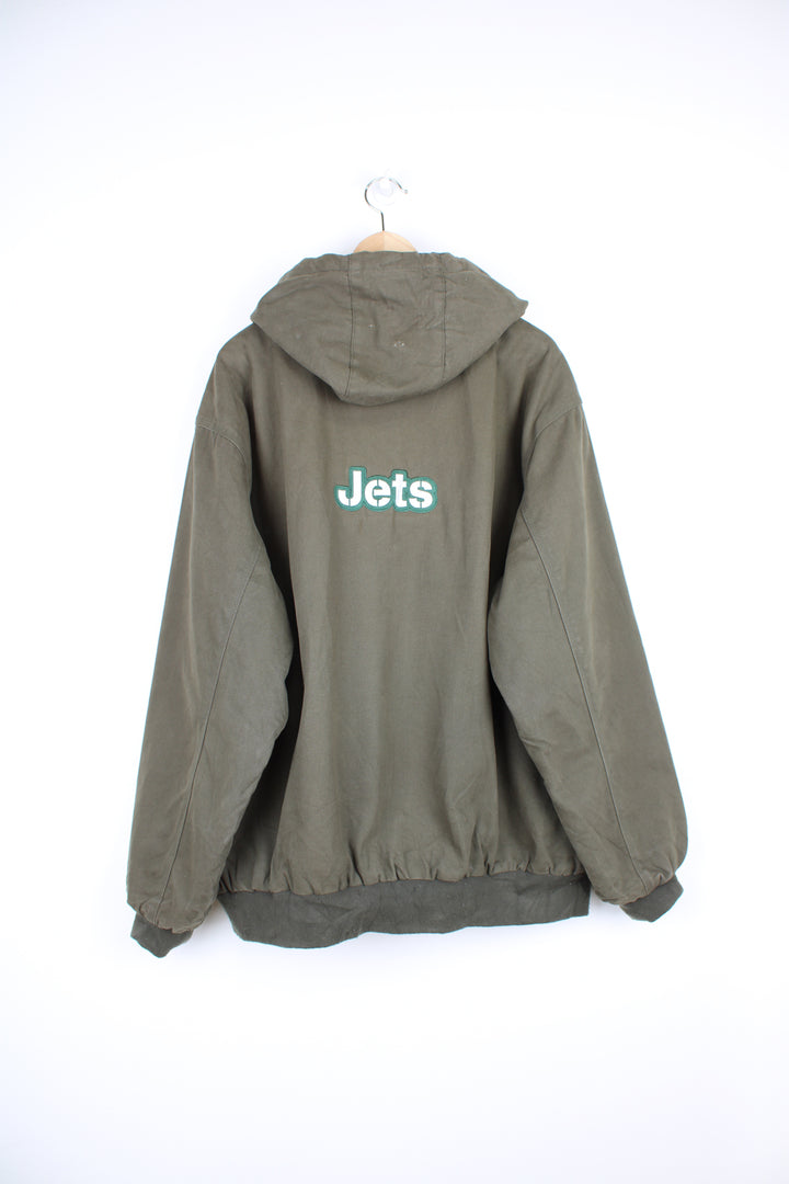 Vintage New York Jets NFL Jacket in a khaki green colourway, workwear style jacket similar to Carhartt Active Jackets, quilted lining, hooded, zip up with side pockets and has the team logo and spell out embroidered on the front and back.