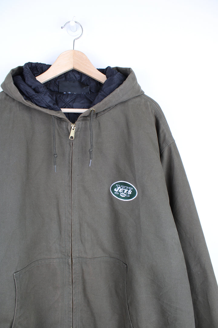 Vintage New York Jets NFL Jacket in a khaki green colourway, workwear style jacket similar to Carhartt Active Jackets, quilted lining, hooded, zip up with side pockets and has the team logo and spell out embroidered on the front and back.