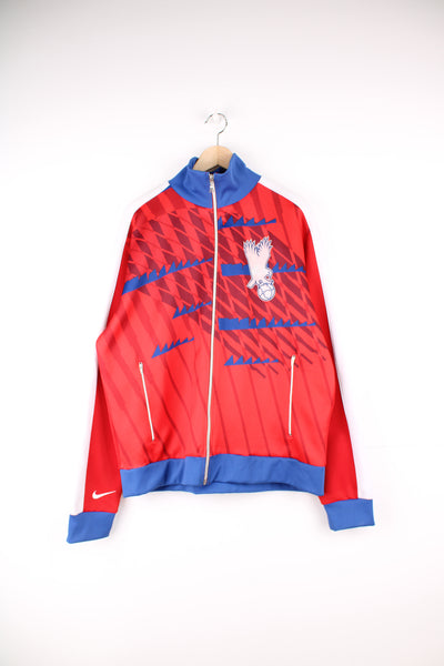 Crystal Palace Nike Tracksuit Jacket in a red, blue and white team colourway, zip up, side pockets and has the logos embroidered on the front and back.