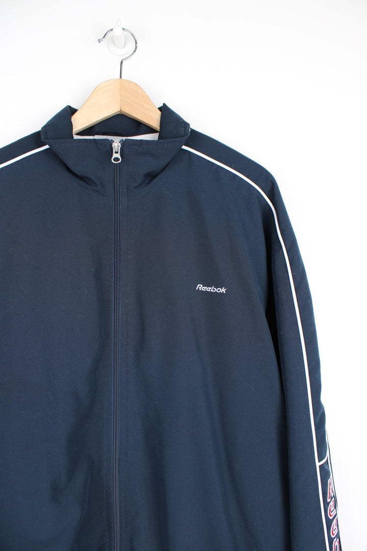 Vintage navy blue Reebok zip through track jacket with embroidered logo on the chest and spell-out down the sleeve