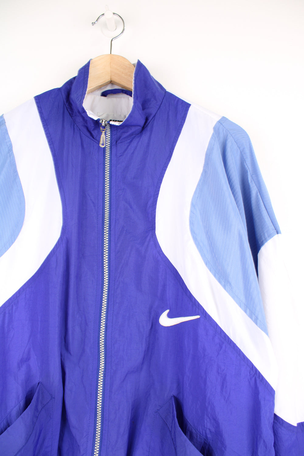 Nike Tracksuit Jacket in a blue and white patterned colourway, zip up with side pockets, and has the swoosh logo embroidered on the front and back.