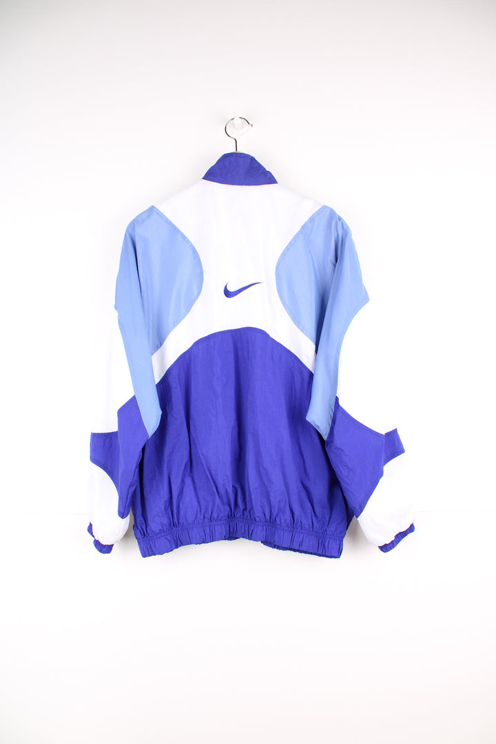 Nike Tracksuit Jacket in a blue and white patterned colourway, zip up with side pockets, and has the swoosh logo embroidered on the front and back.