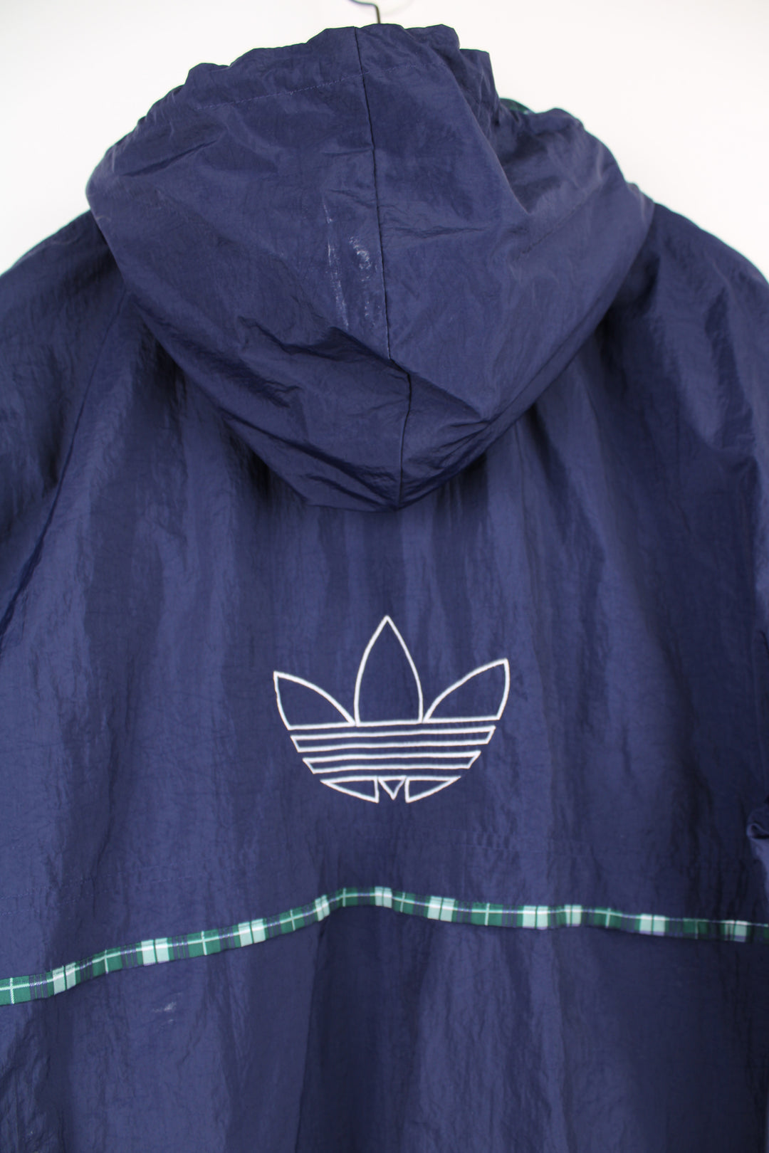 Adidas Pullover Windbreaker in a blue colourway with green and white tartan pattern throughout, hooded, half zip up, big pouch pocket, and has the logo embroidered on the front and back.