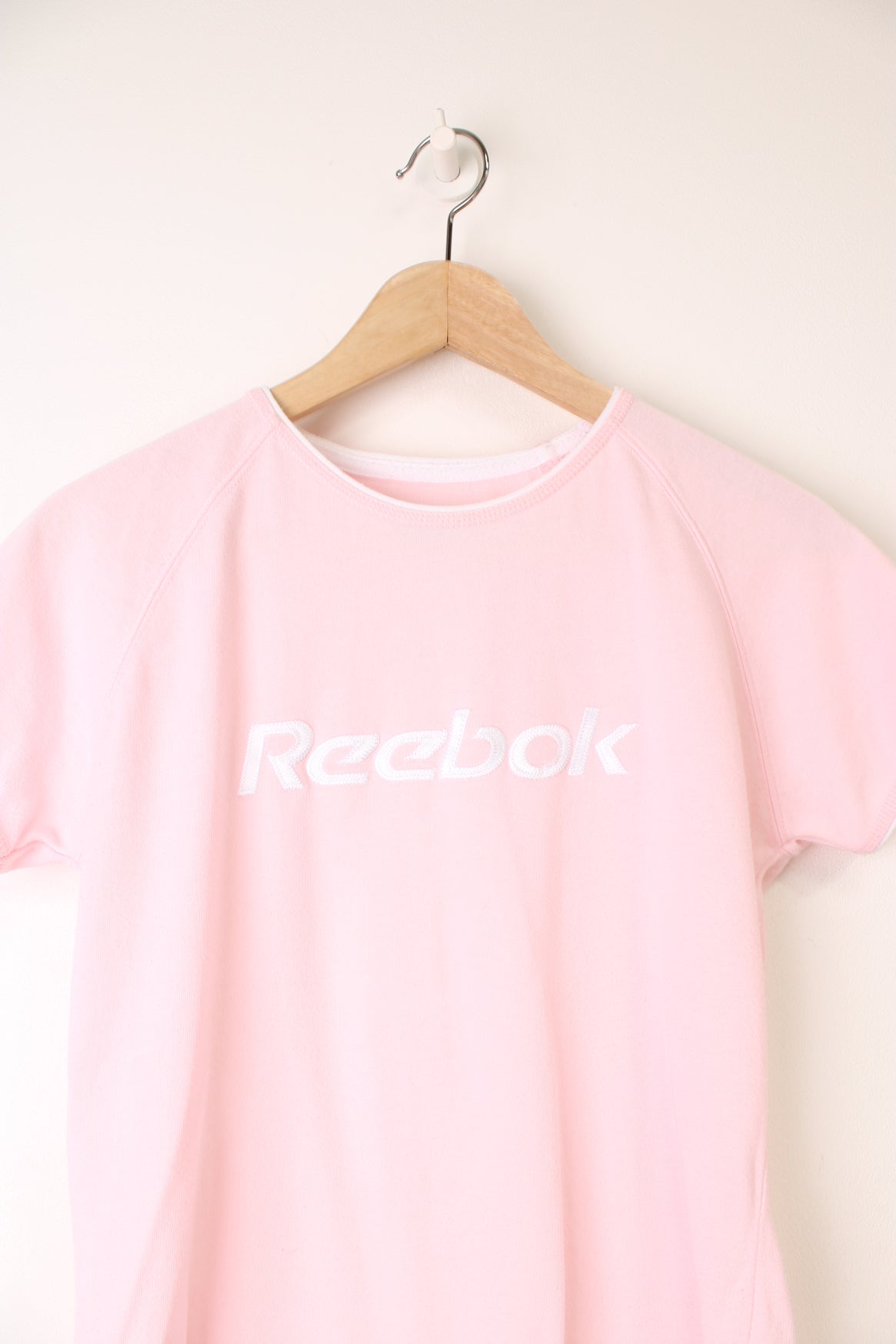 Y2K style pale pink baby tee by Reebok, features embroidered spell-out logo across the chest