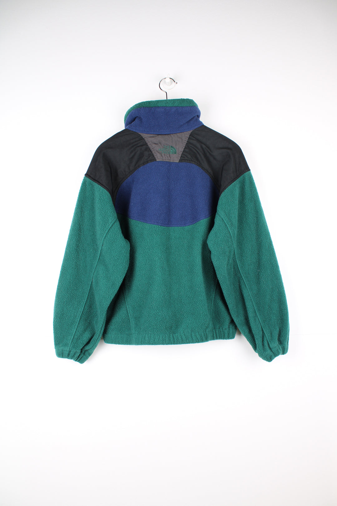 The North Face Fleece in a green, blue and black colourway, zip up with side pockets, and has the logo embroidered on the front and back.