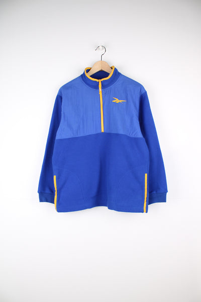 Reebok Fleece in a blue and yellow colourway, half zip up, side pockets and has the logo embroidered on the front.