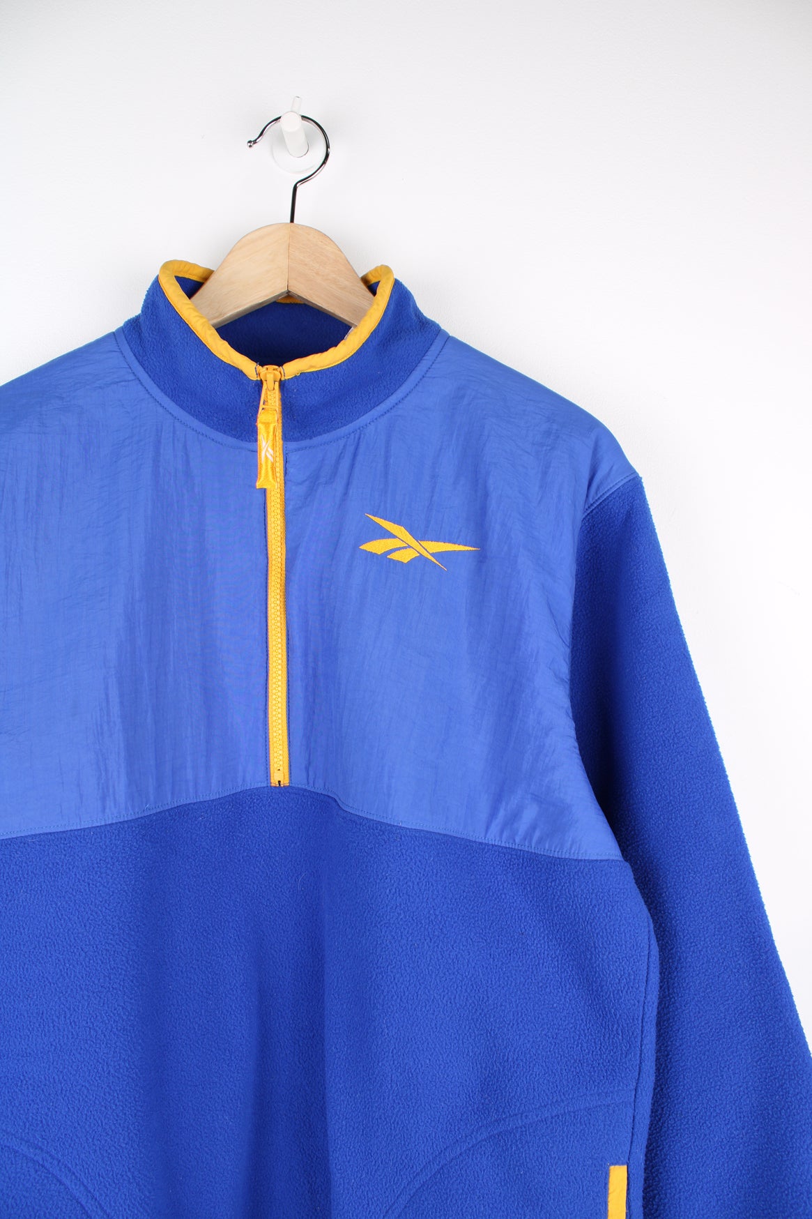 Reebok Fleece in a blue and yellow colourway, half zip up, side pockets and has the logo embroidered on the front.