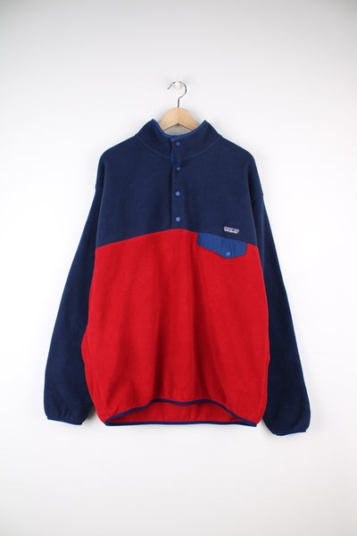 Patagonia Synchilla Fleece in a blue and red colourway, button up, chest pocket and has the logo embroidered on the front.