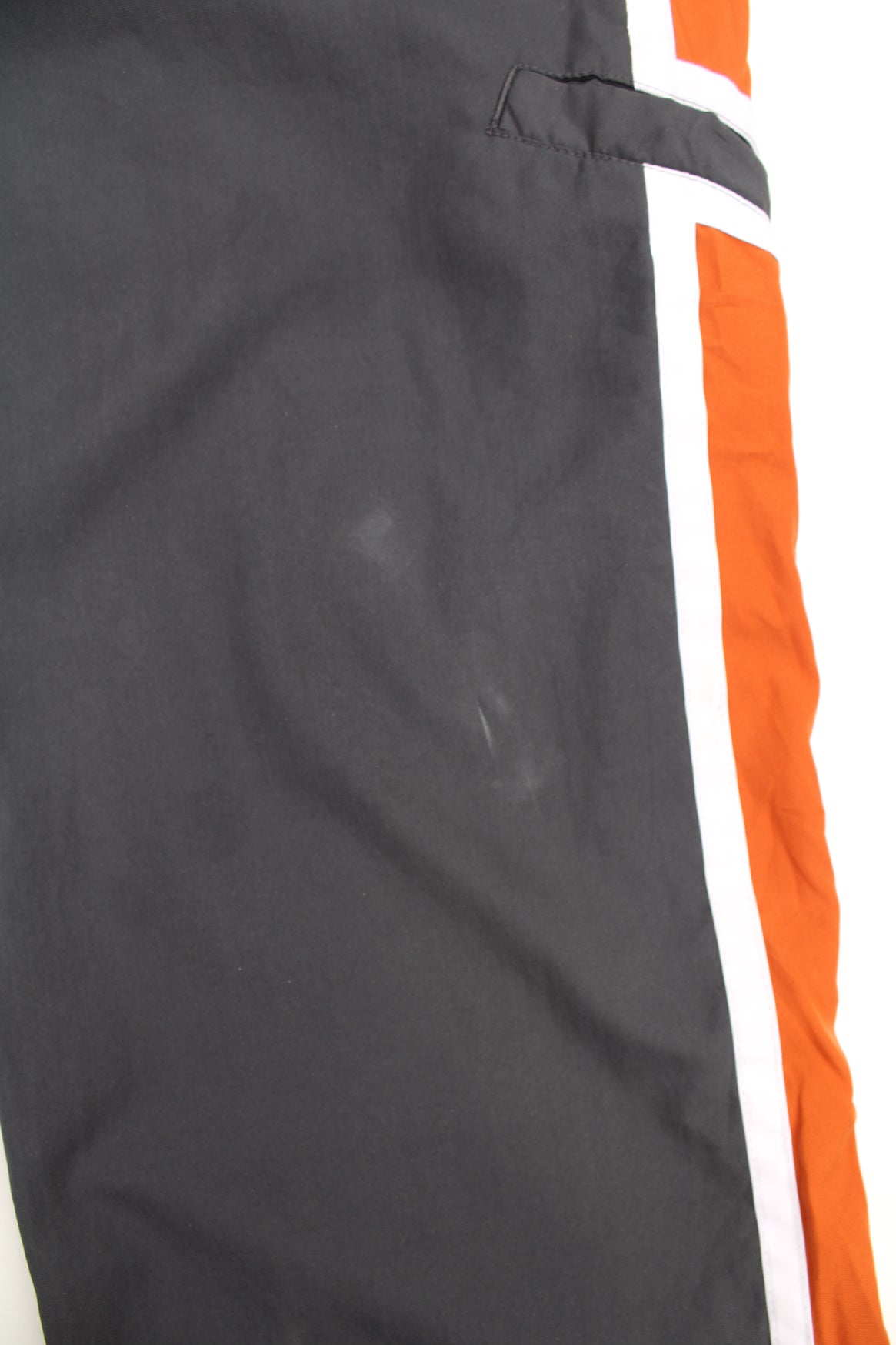 Nike Tracksuit Bottoms in a grey, white and orange colourway with stripes going down the sides, adjustable waist, cargo style pocket, and has the swoosh logo embroidered on the front.