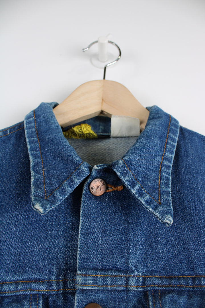 Vintage Wrangler Denim Jacket in a blue colourway, button up, double chest pockets, and has logo embroidered on the chest.