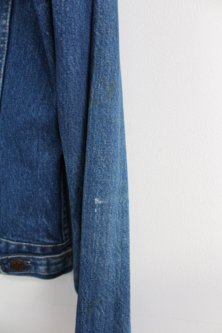 Vintage Levi's Denim Jacket in a blue colourway, button up, double chest pockets, and has orange tab logo embroidered on the chest.