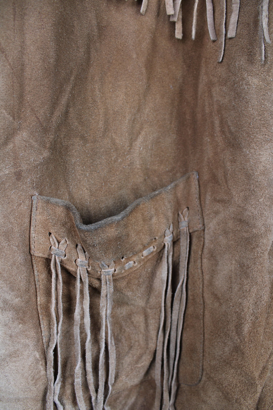 Vintage 90's DKNY fringe jacket. Tan suede jacket with fringe and whip stitch detail. The jacket is fully lined and closes with wooden toggle style buttons down the front. Fair condition - The jacket is discoloured in places and is missing some tassels on the shoulder and pocket. Size in Label: Womens L 12 - 14 