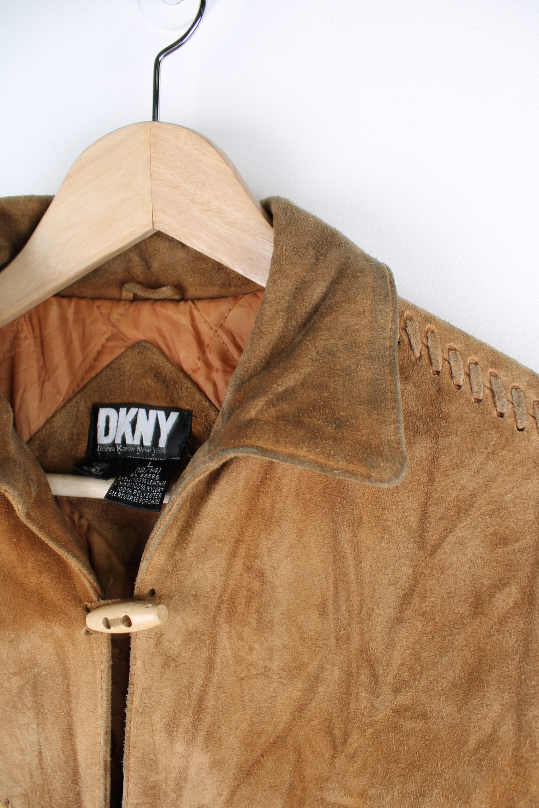 Vintage 90's DKNY fringe jacket. Tan suede jacket with fringe and whip stitch detail. The jacket is fully lined and closes with wooden toggle style buttons down the front. Fair condition - The jacket is discoloured in places and is missing some tassels on the shoulder and pocket. Size in Label: Womens L 12 - 14 