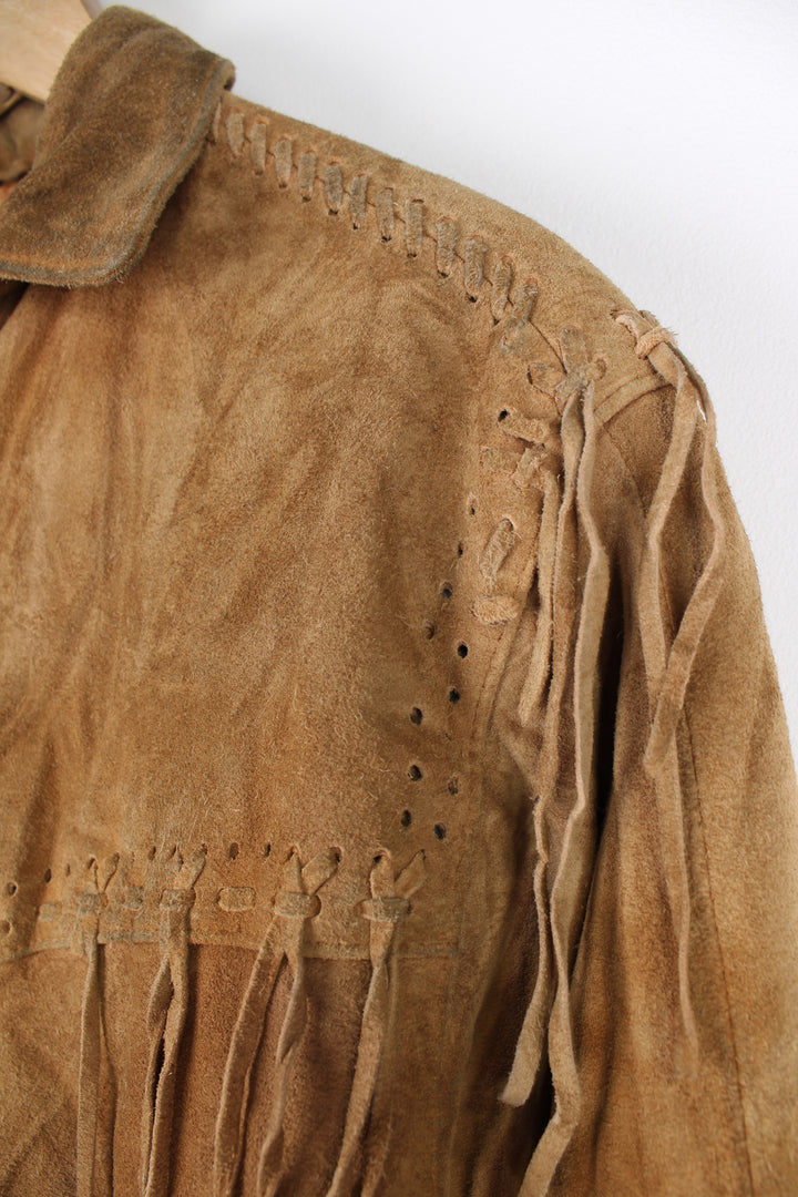 Vintage 90's DKNY fringe jacket. Tan suede jacket with fringe and whip stitch detail. The jacket is fully lined and closes with wooden toggle style buttons down the front. Fair condition - The jacket is discoloured in places and is missing some tassels on the shoulder and pocket. Size in Label: Womens L 12 - 14 