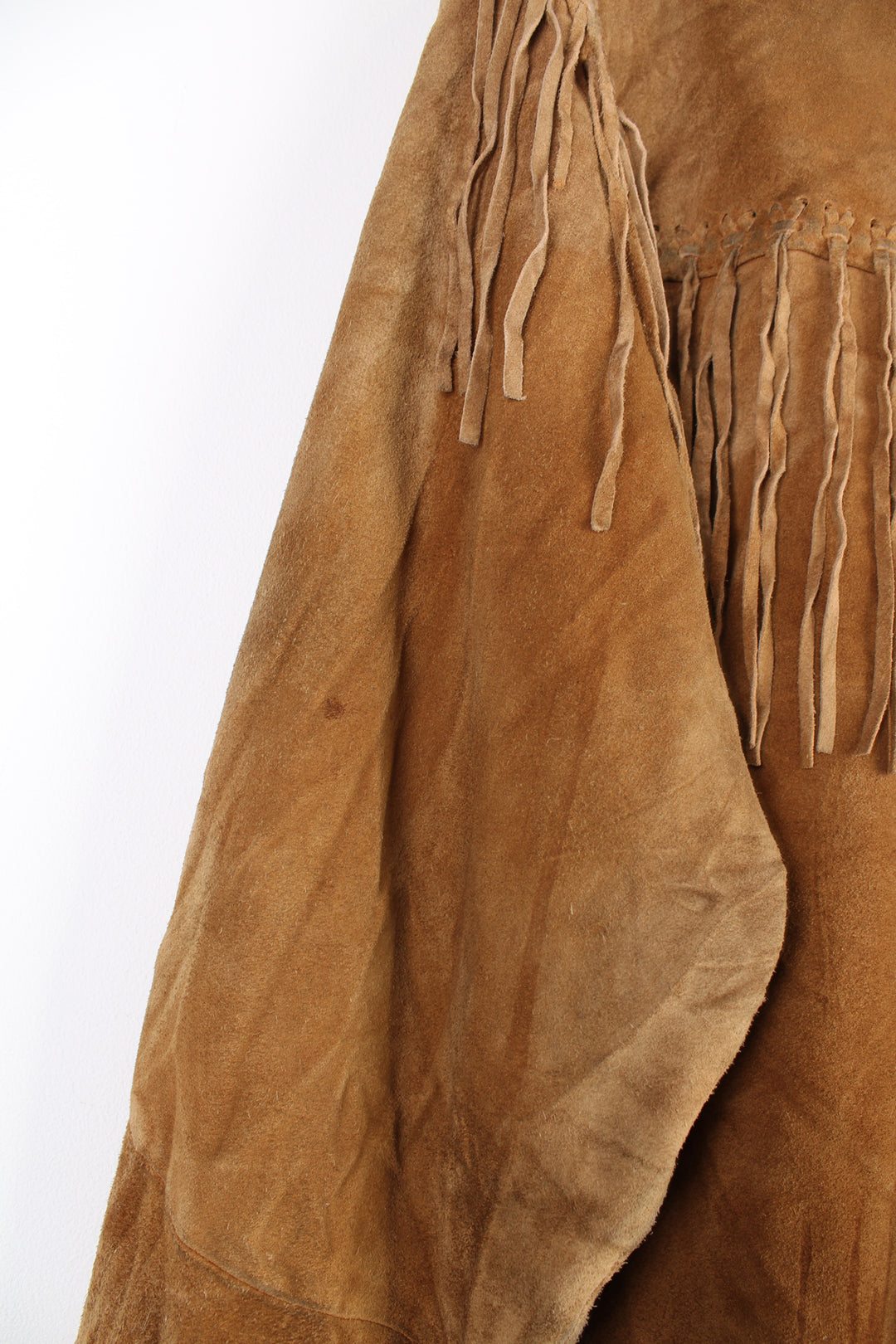 Vintage 90's DKNY fringe jacket. Tan suede jacket with fringe and whip stitch detail. The jacket is fully lined and closes with wooden toggle style buttons down the front. Fair condition - The jacket is discoloured in places and is missing some tassels on the shoulder and pocket. Size in Label: Womens L 12 - 14 