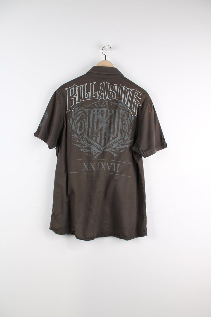 Billabong Short Sleeved Shirt in a khaki and grey colourway, button up, double chest pockets, and has logo embroidered on the front and big back graphic.