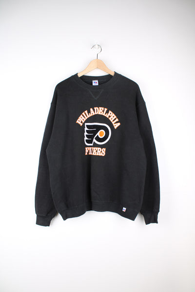 Philadelphia Flyers NHL Sweatshirt in a black colourway, on a Russel Athletic sweatshirt, and has the logo and spell out printed on the front.