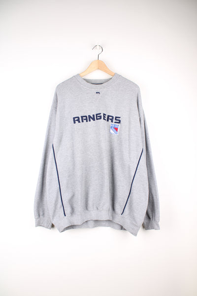 Vintage Lee Sport, New York Rangers NHL Sweatshirt in a grey colourway, blue stripes going down the sides, and has the logos and spell out embroidered on the front.