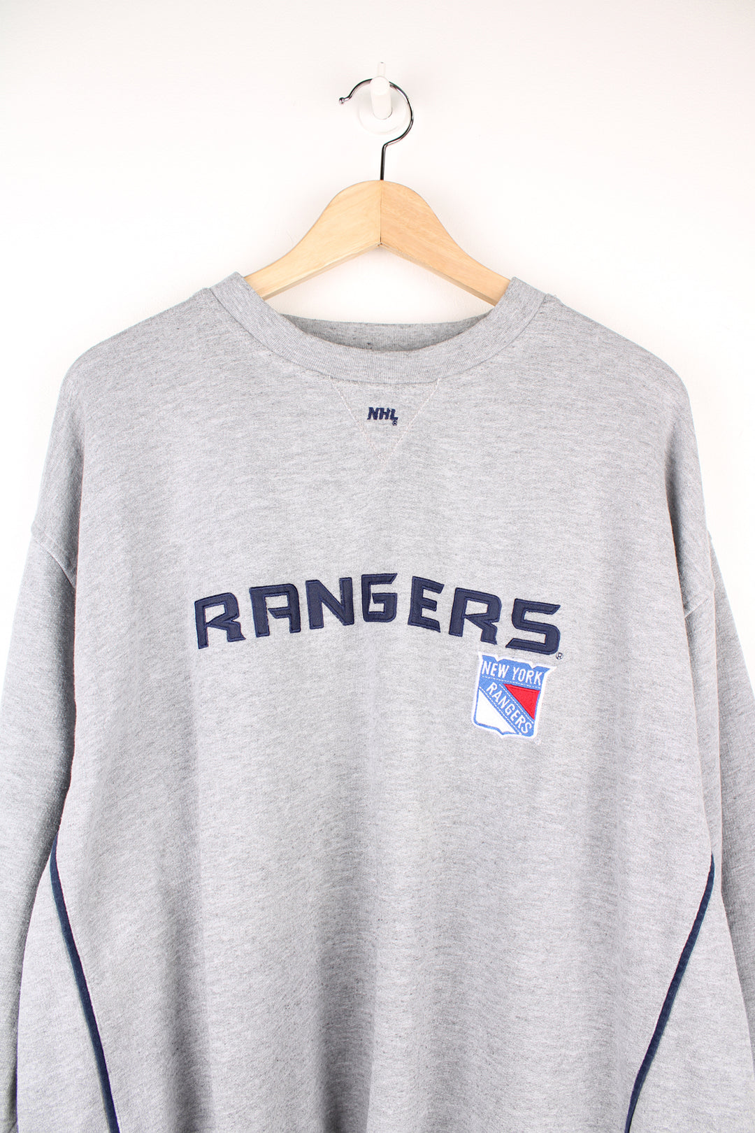 Vintage Lee Sport, New York Rangers NHL Sweatshirt in a grey colourway, blue stripes going down the sides, and has the logos and spell out embroidered on the front.