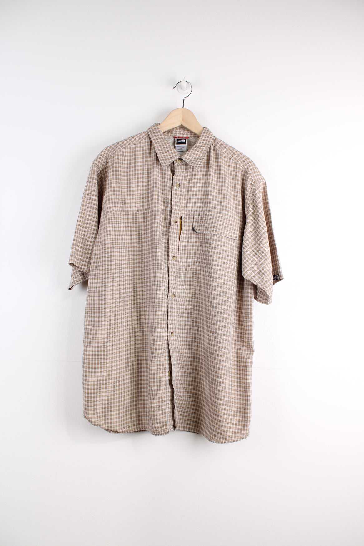 The North Face Short Sleeve Plaid Shirt in a tan and orange colourway, button up with chest pockets, and logo embroidered on the side.