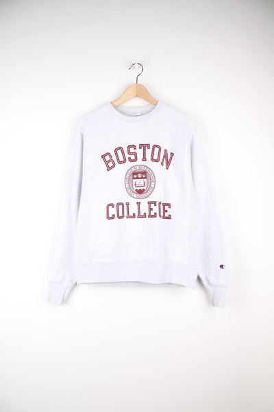 Champion Reverse Weave, Boston College Sweatshirt in a grey and burgundy colourway, and has the college spell out and logo printed on the front, as well as the champion logo embroidered on the left sleeve.