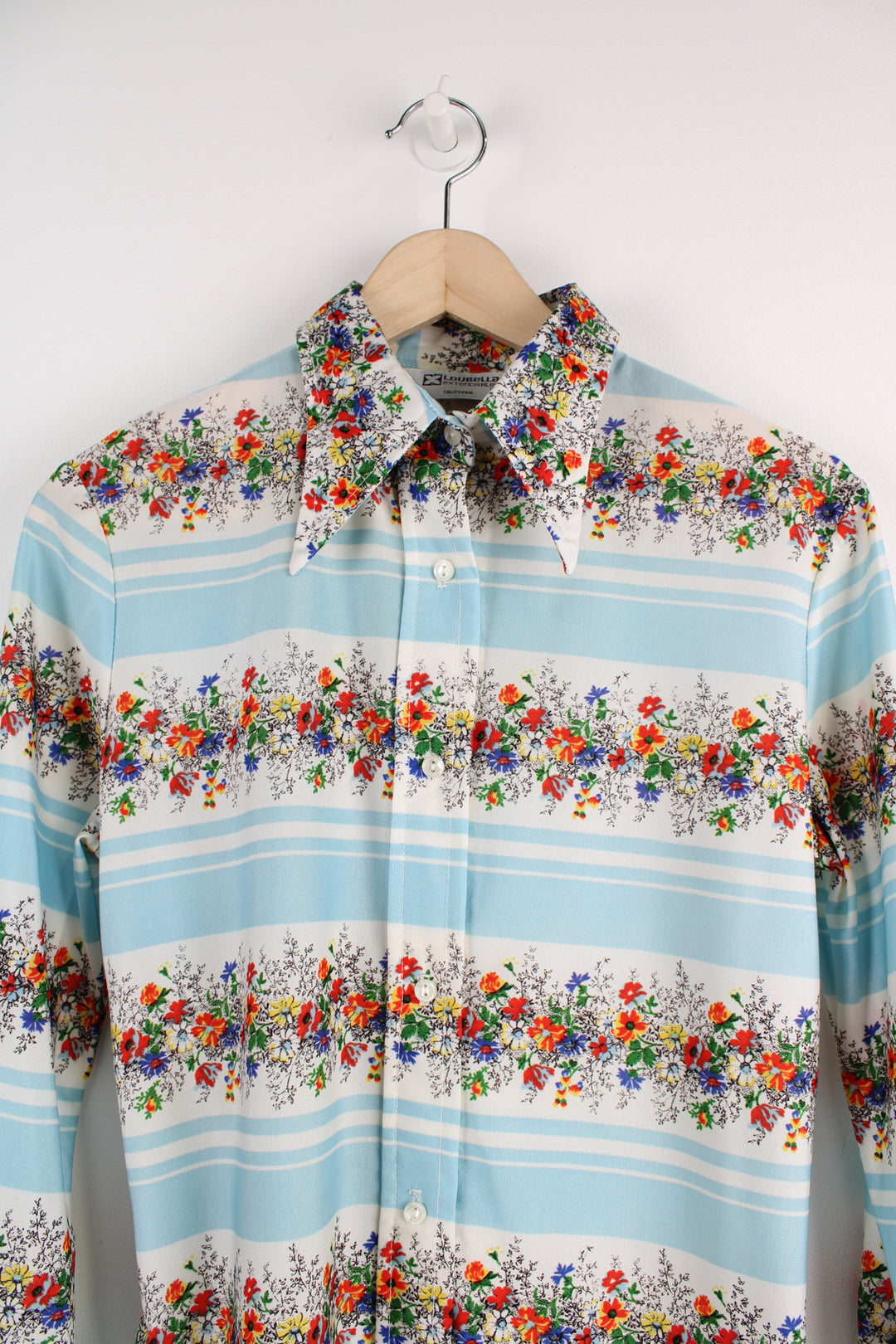 Vintage 70's Loubella Patterned Blouse in a white and blue striped colourway with multicoloured flowers printed across, button up, and has a dagger collar.