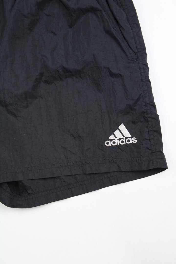 00's black Adidas sports shorts with elasticated waist and drawstring tie. Features white three stripe detail down the sides and has an embroidered logo on the front leg and printed logo on the back.