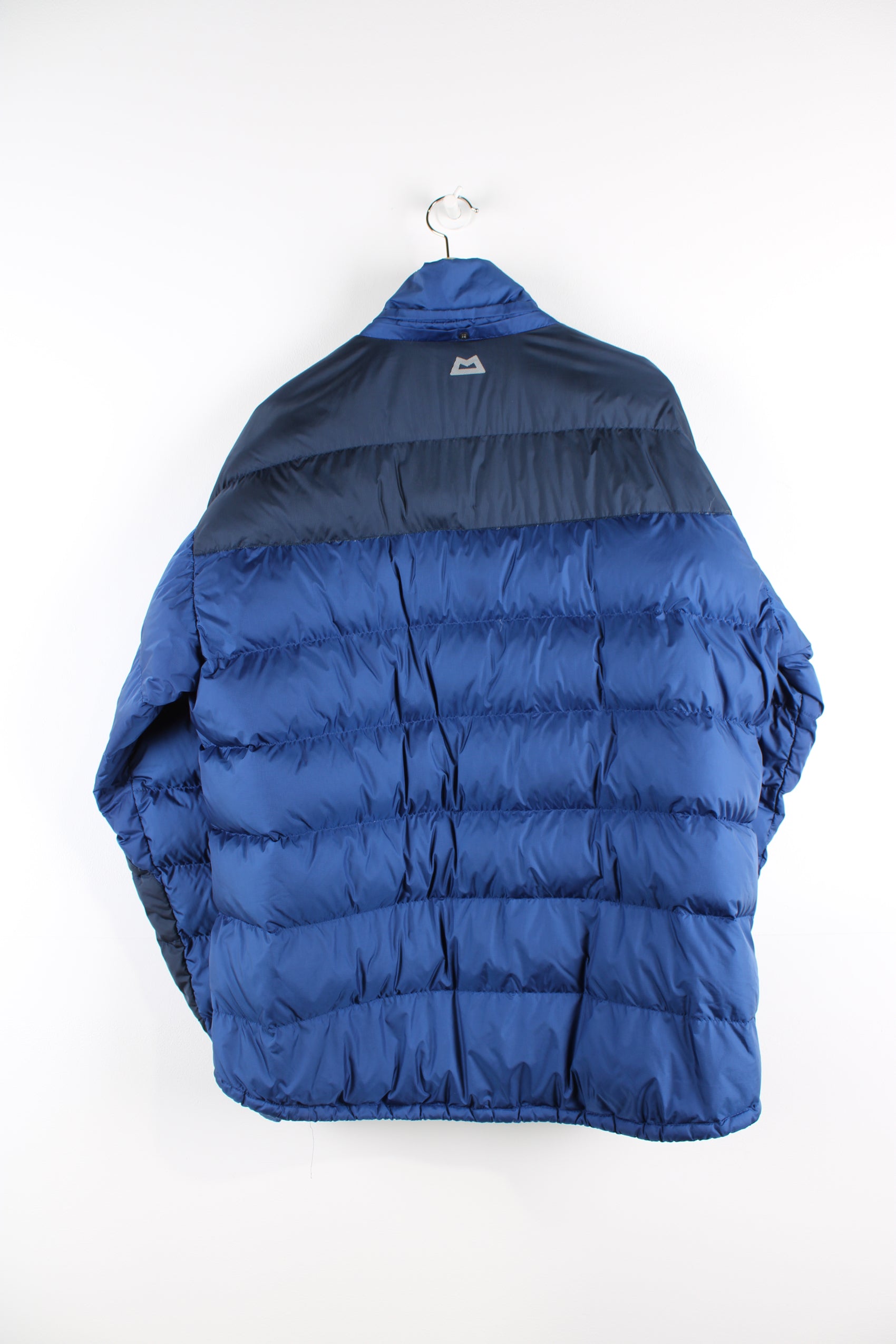 Navy blue Mountain Equipment puffer jacket with drawstring hem and zip up pockets