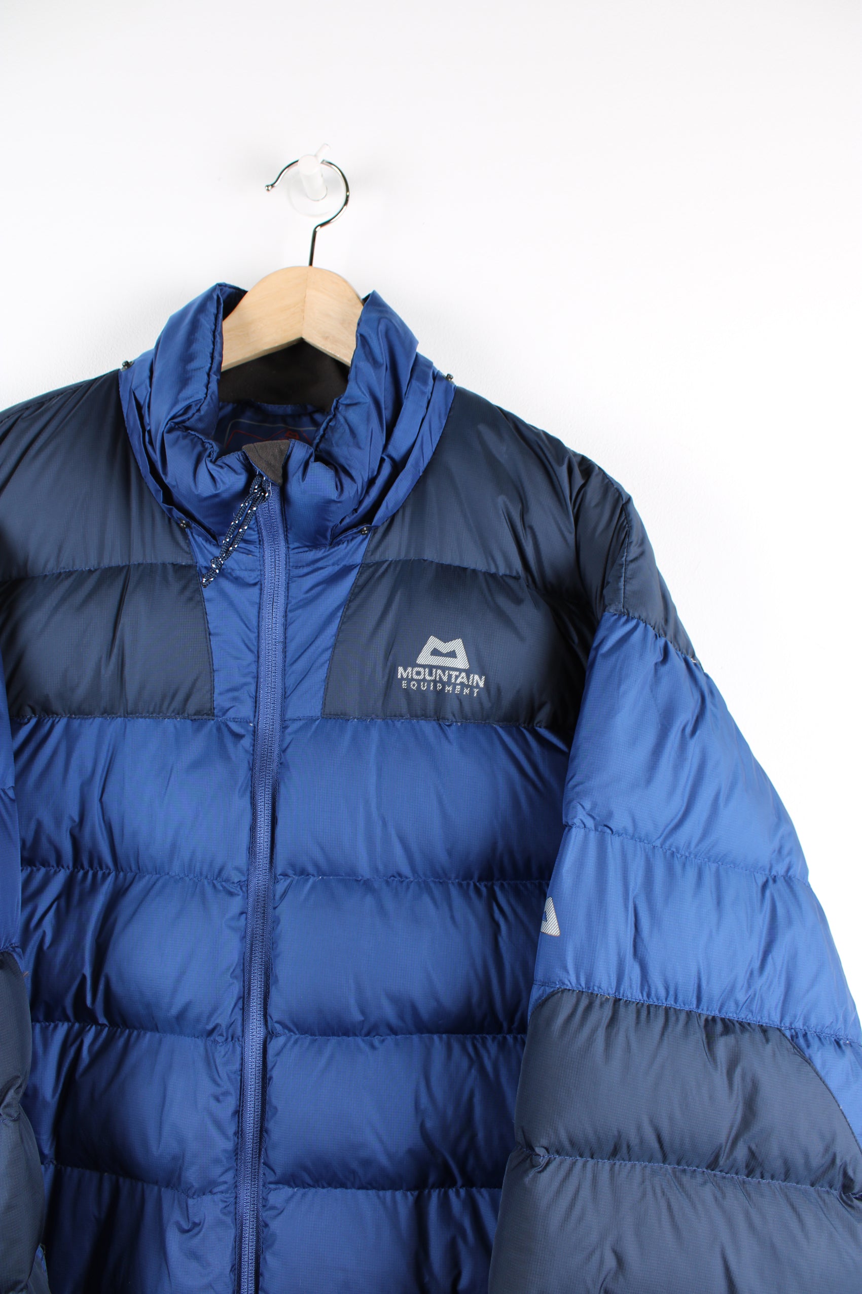 Navy blue Mountain Equipment puffer jacket with drawstring hem and zip up pockets