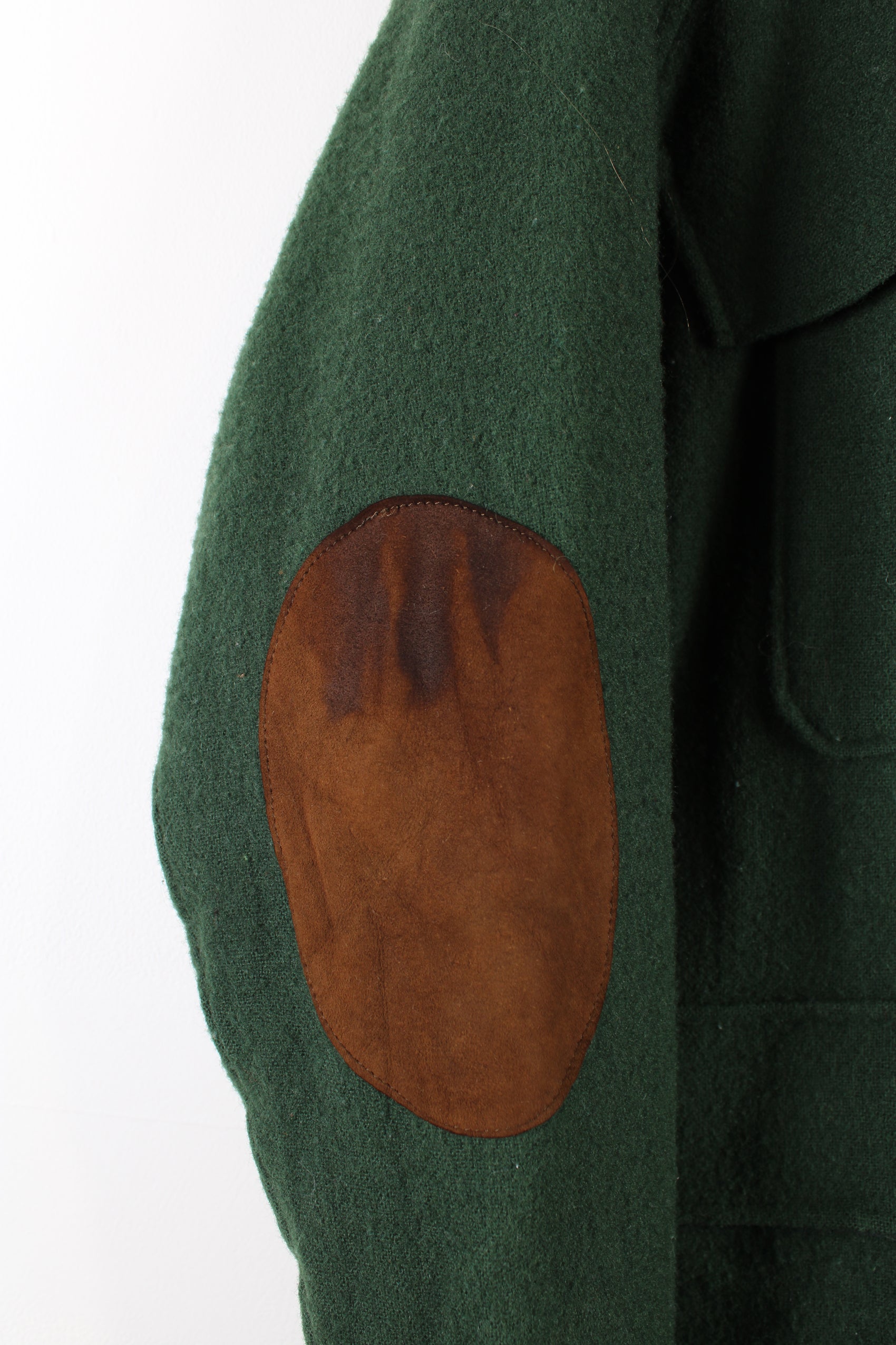 Vintage Woolrich wool chore jacket in green, button up with multiple pockets, tartan lining and brown elbow pads.