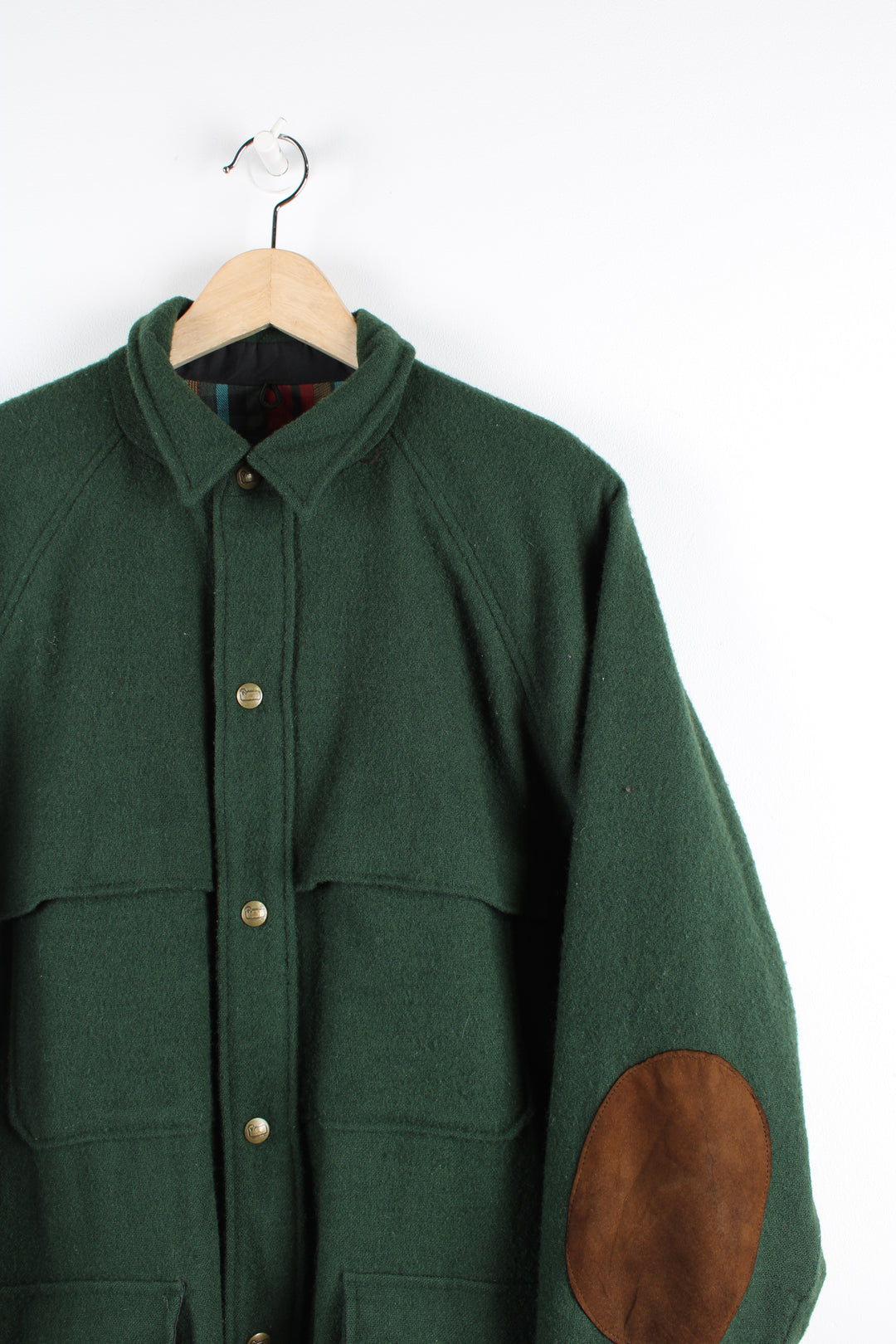 Vintage Woolrich wool chore jacket in green, button up with multiple pockets, tartan lining and brown elbow pads.