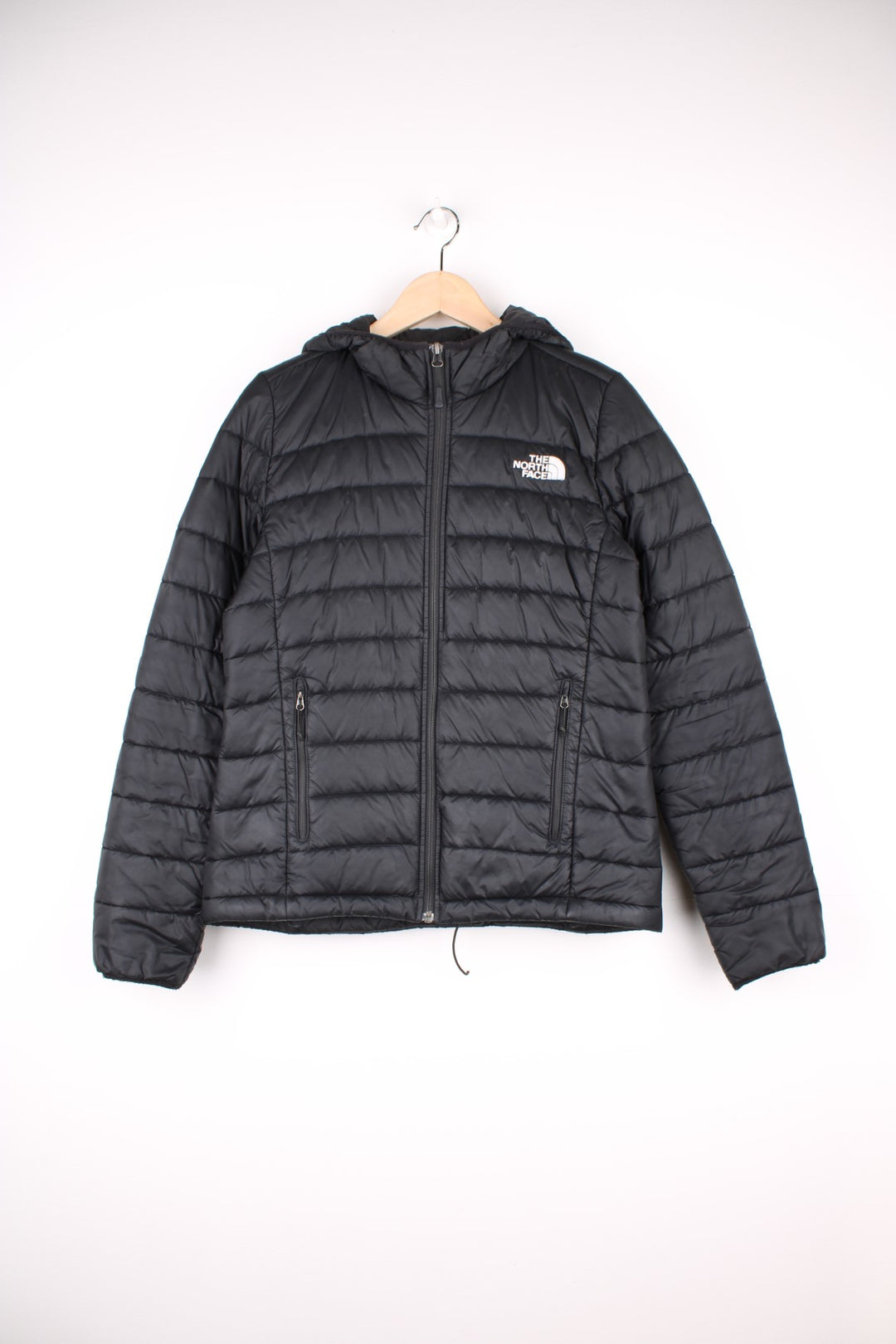 The North Face Puffer Jacket in a black colourway, zip up with side pockets, hooded, insulated, and has the logo embroidered on the front and back.