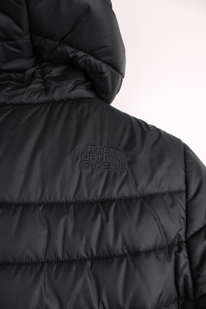 The North Face Puffer Jacket in a black colourway, zip up with side pockets, insulated, hooded, and has the logo embroidered on the front and back.