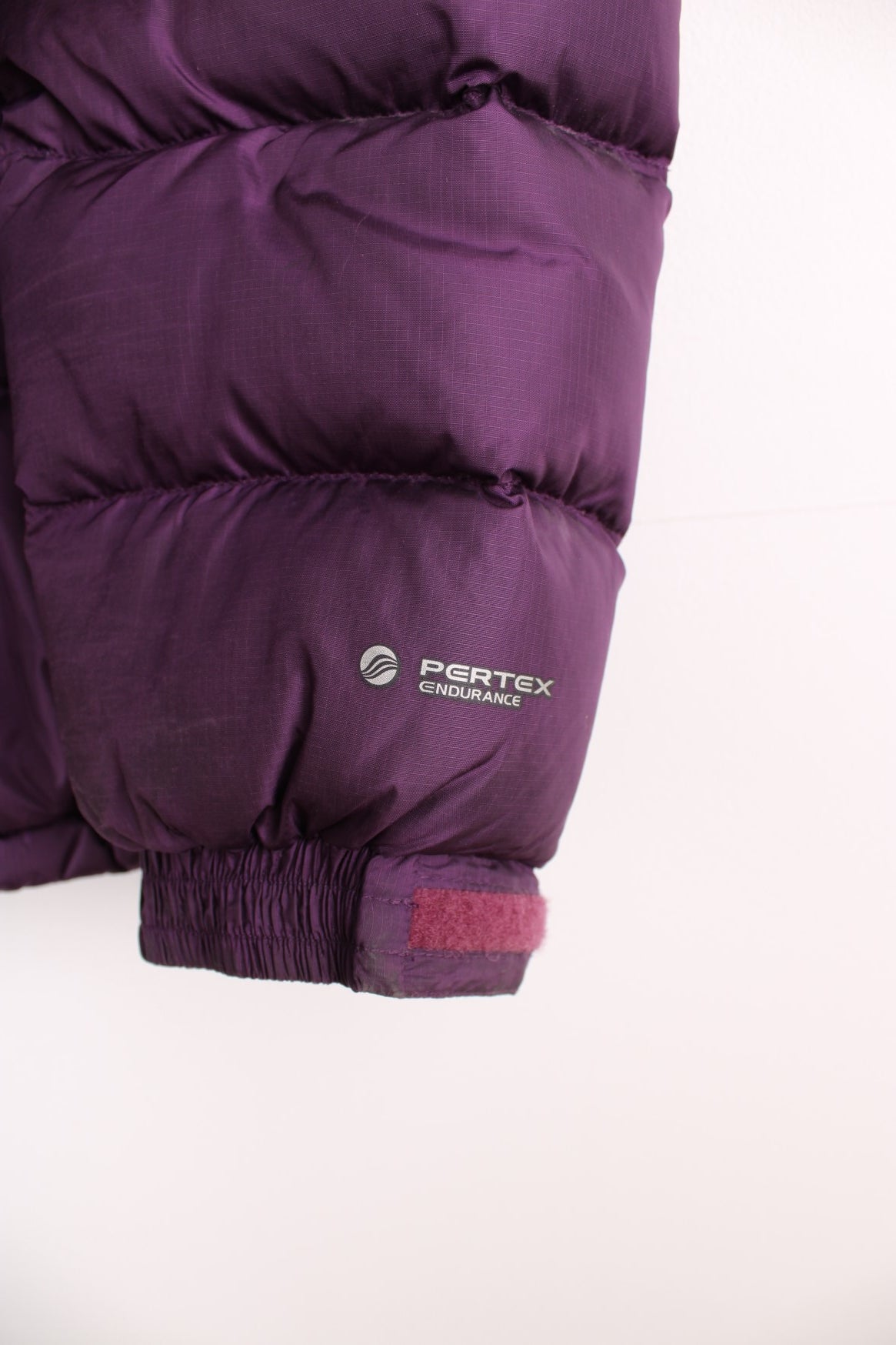 Rab Extreme Puffer Jacket in a purple colourway, zip up with side pockets, has a detachable hood, insulated, and has the logo embroidered on the front.